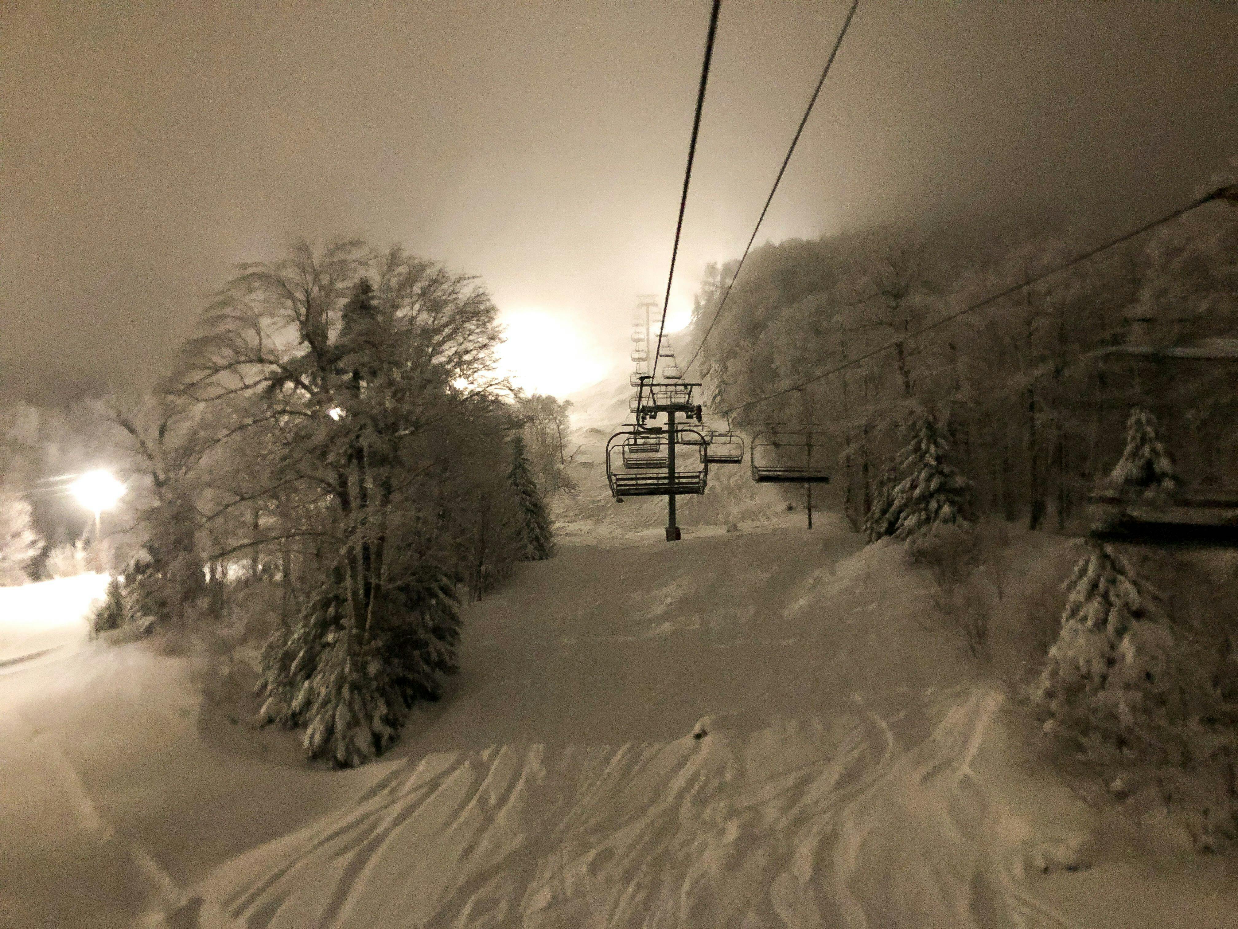 A chairlift over a lit up ski slope at night.