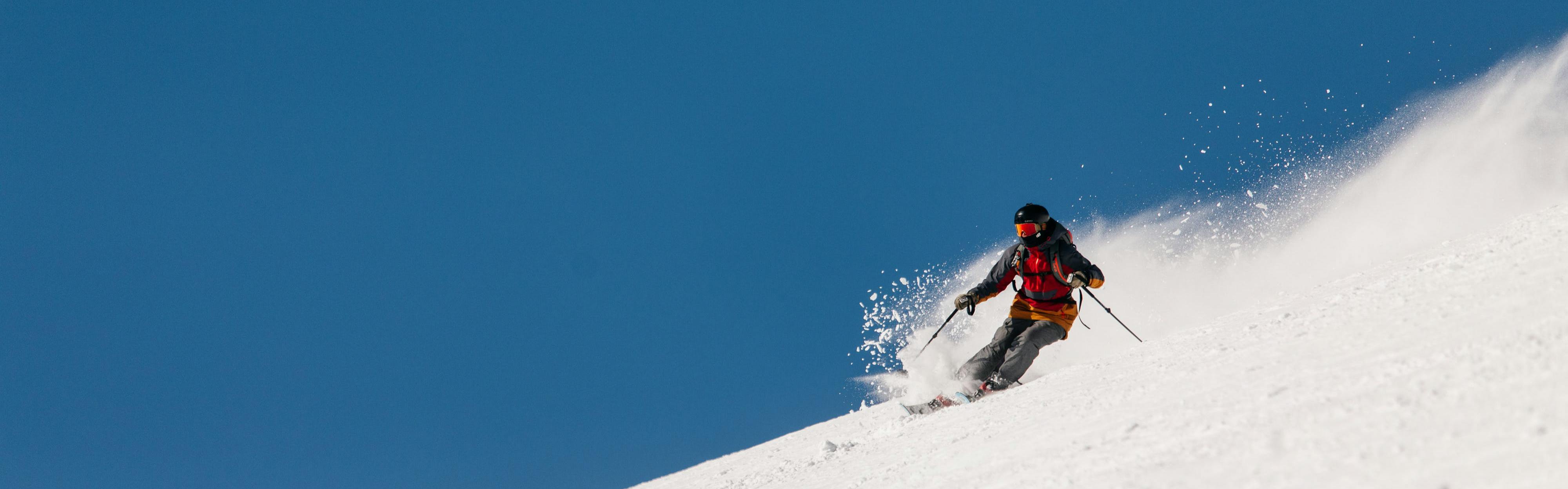 A skier wearing a red jacket skis down a hill.