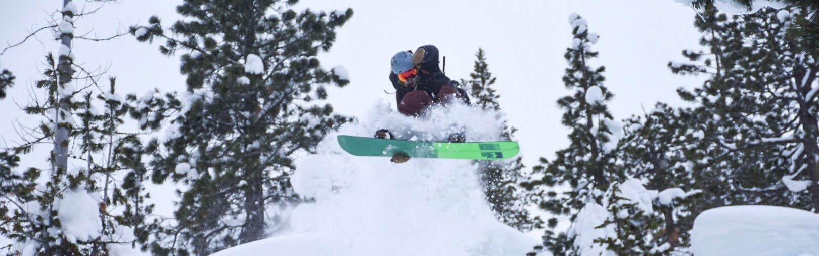 A snowboarder hitting a powdery jump. 