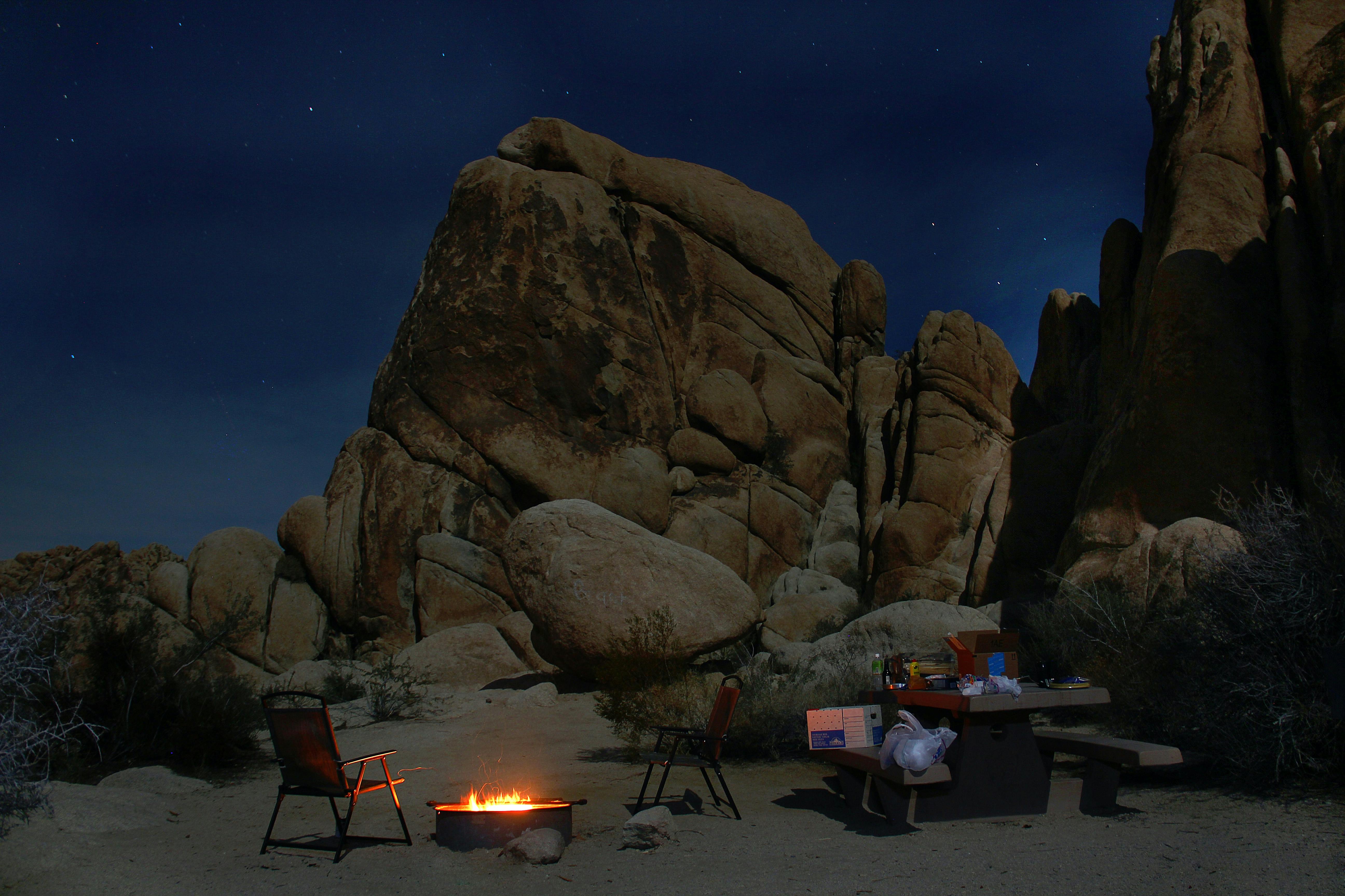 A campsite at night alongside a large rock formation