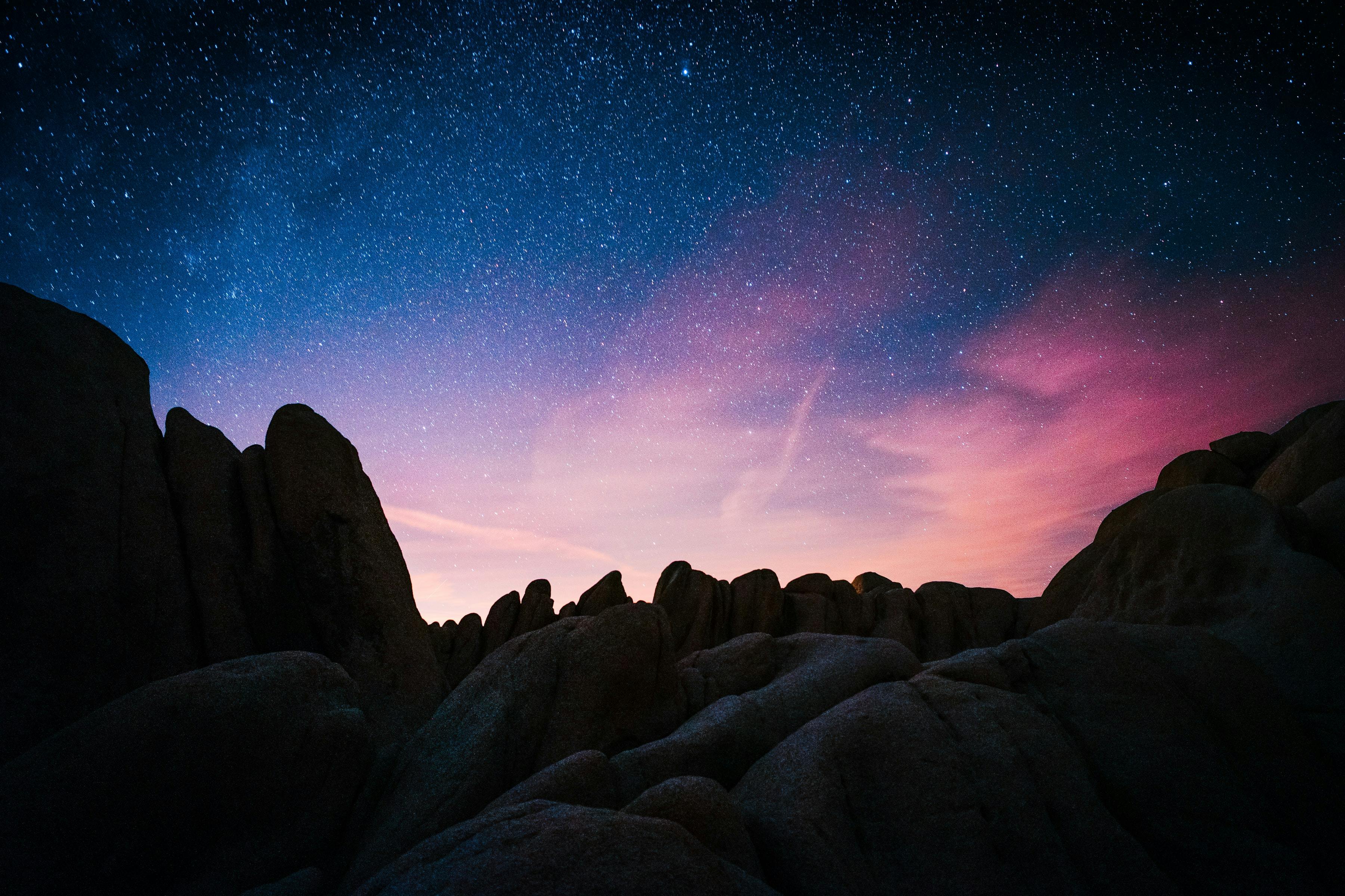 Brightly colored sky with stars over some rock formations.