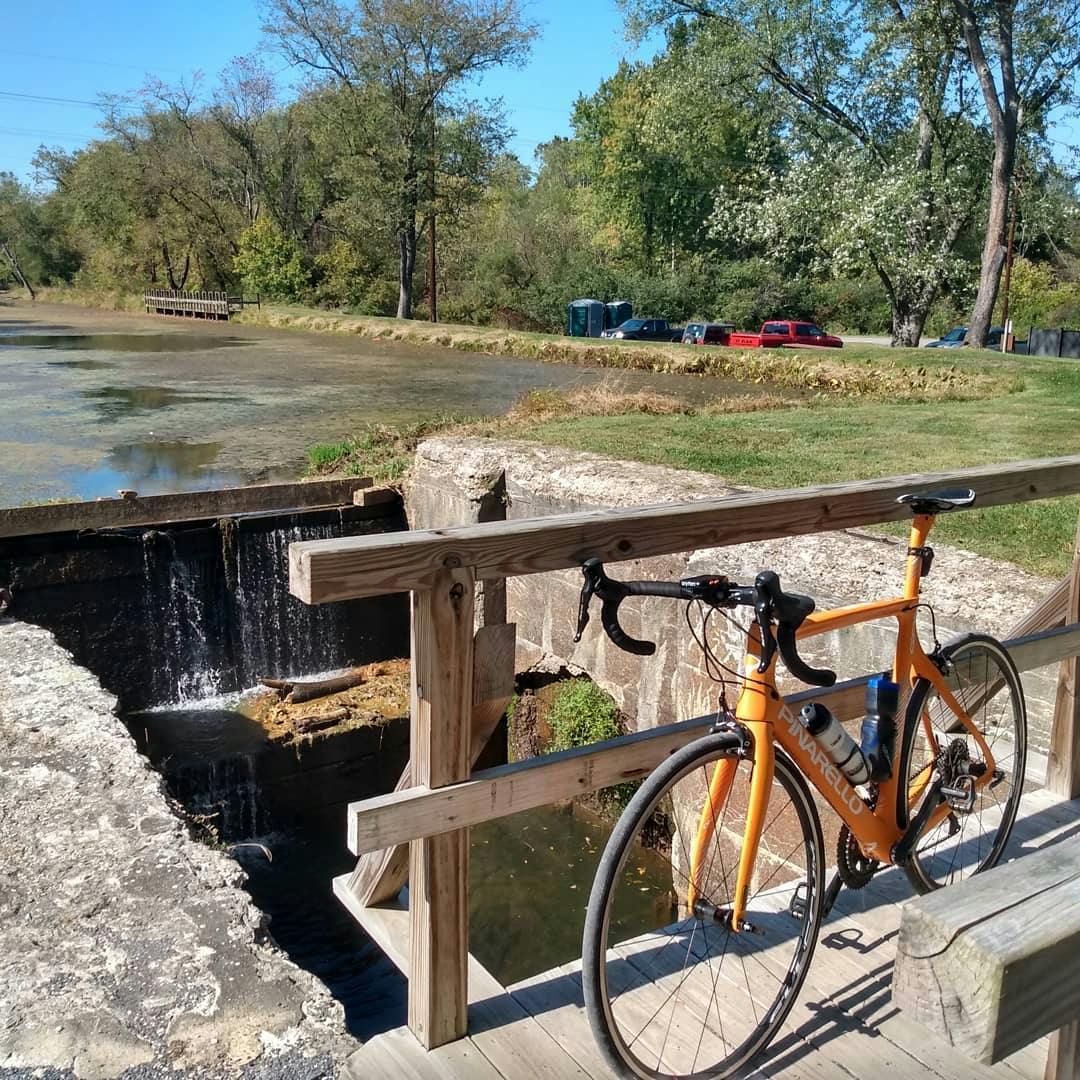 The author's orange bike rests against a wooden bridge.