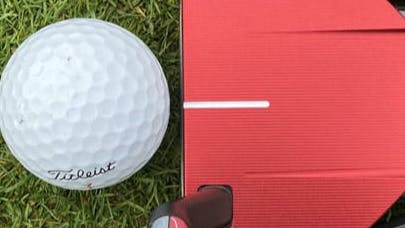 The TaylorMade Spider GT Red #3 Putter in front of a golf ball. 