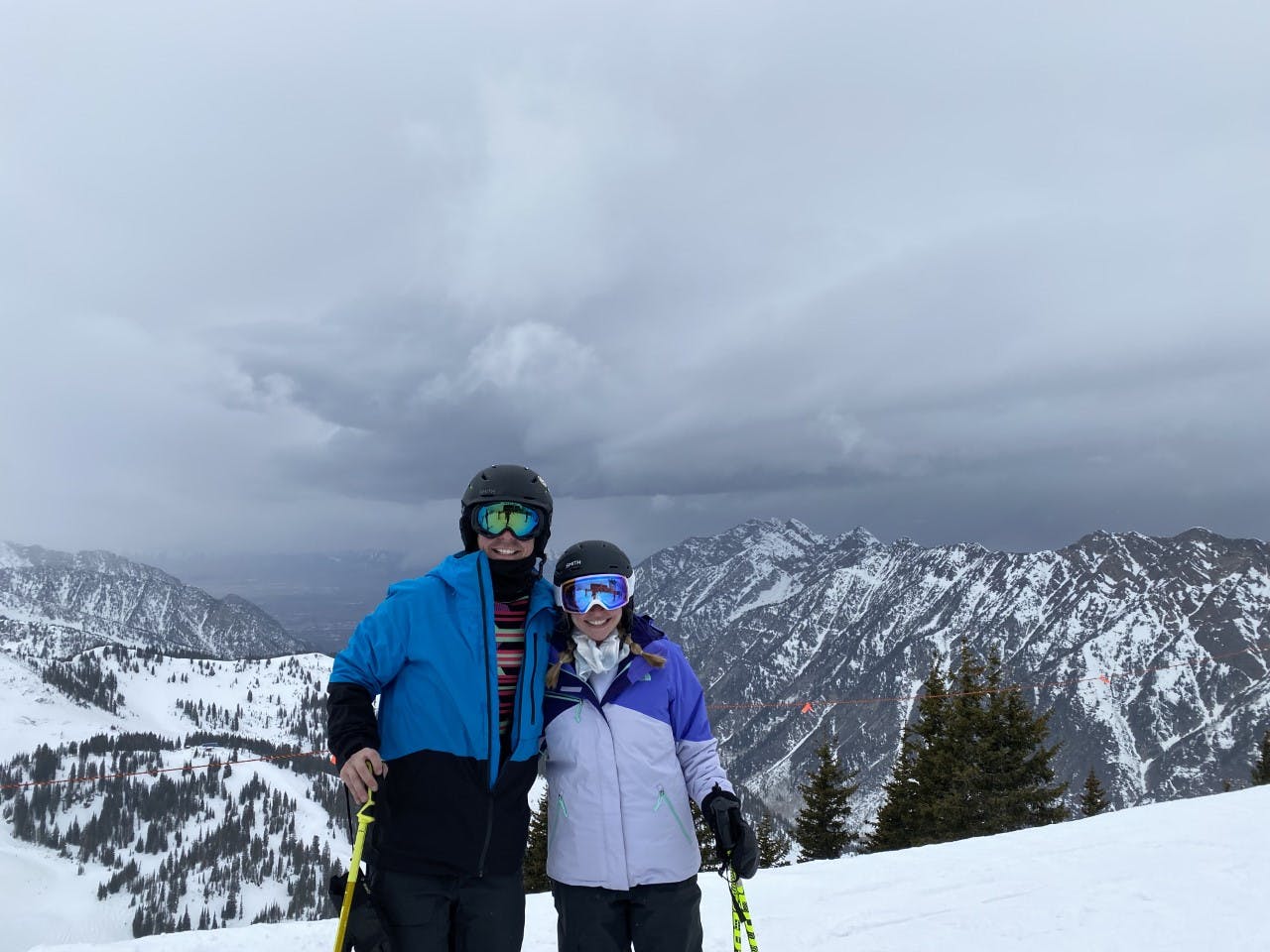 Two skier stand at the top of Snowbird ski resort. Both are wearing full ski gear.