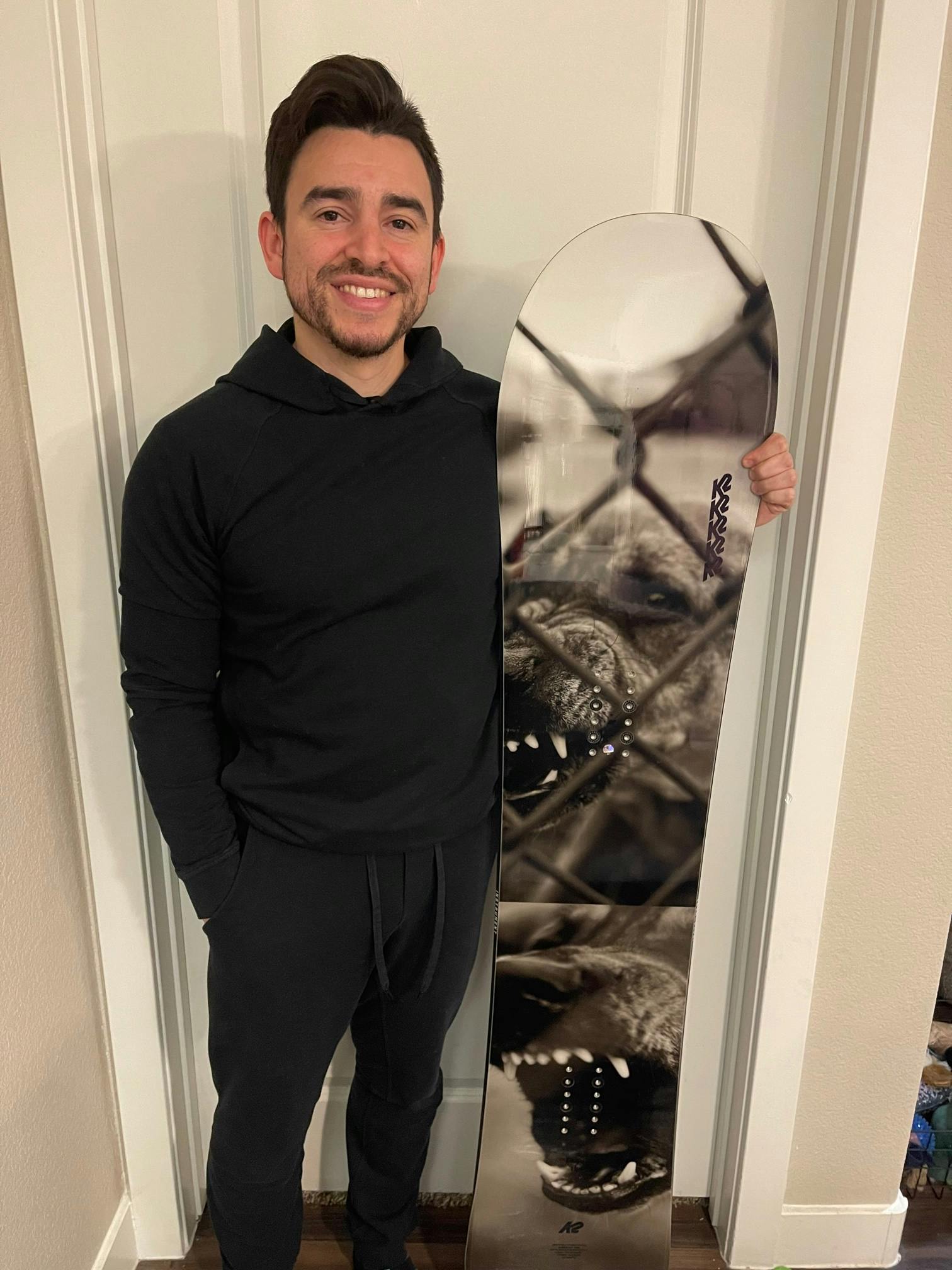 A man standing with the K2 Instrument Snowboard.