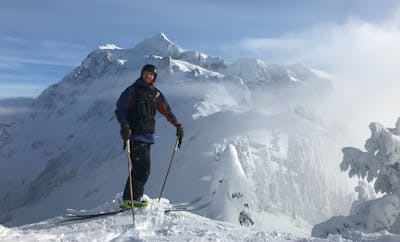A man standing on skis at the top of a mountain. 