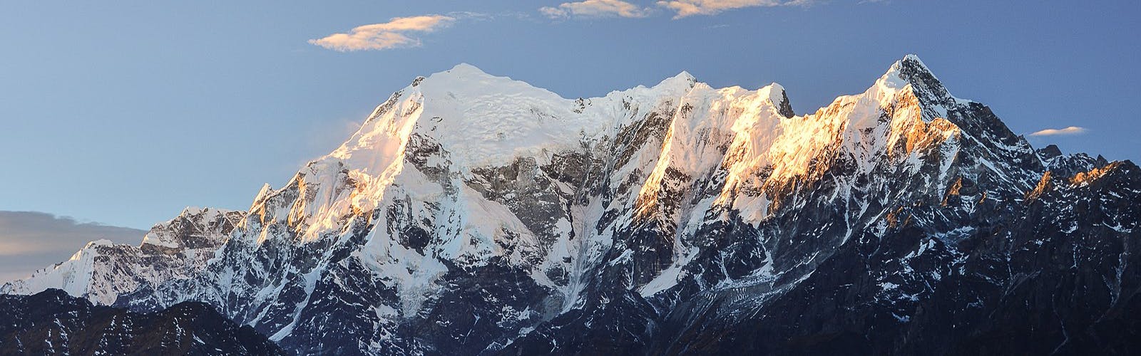 Himalayan peaks topped with snow against a pale blue sky.