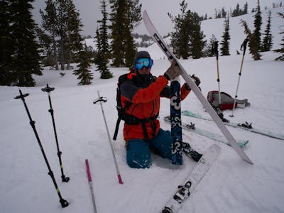 A skier kneels taking the skins off his skis while wearing the Helly Hansen Men's Ridge Infinity Shell Jacket.