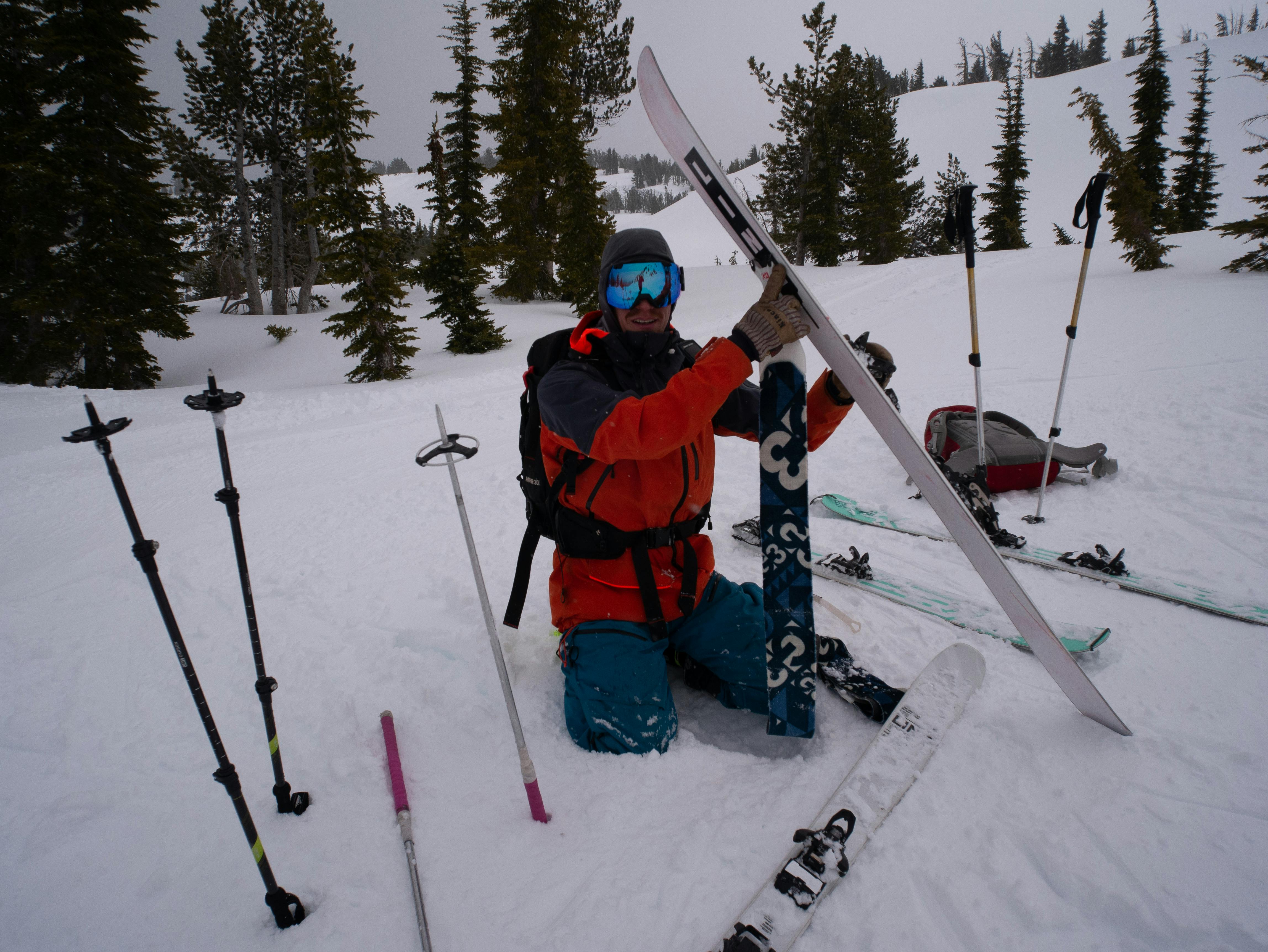 A backcountry skier removing his ski skins at the top of a run. 