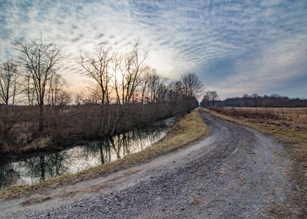 A gravel path winding alongside a narrow river in the early evening