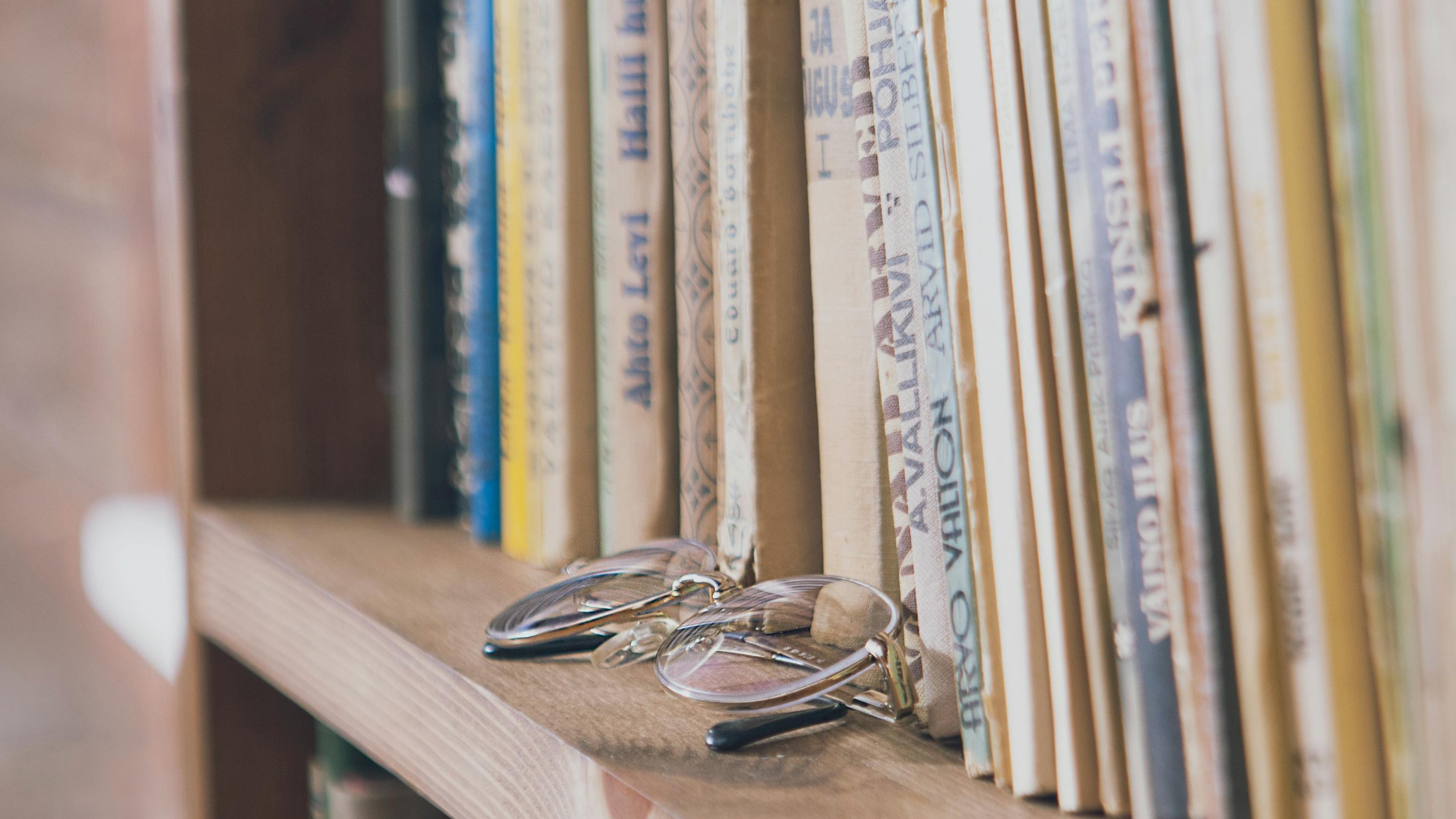 A pair of glasses sits on a bookshelf.