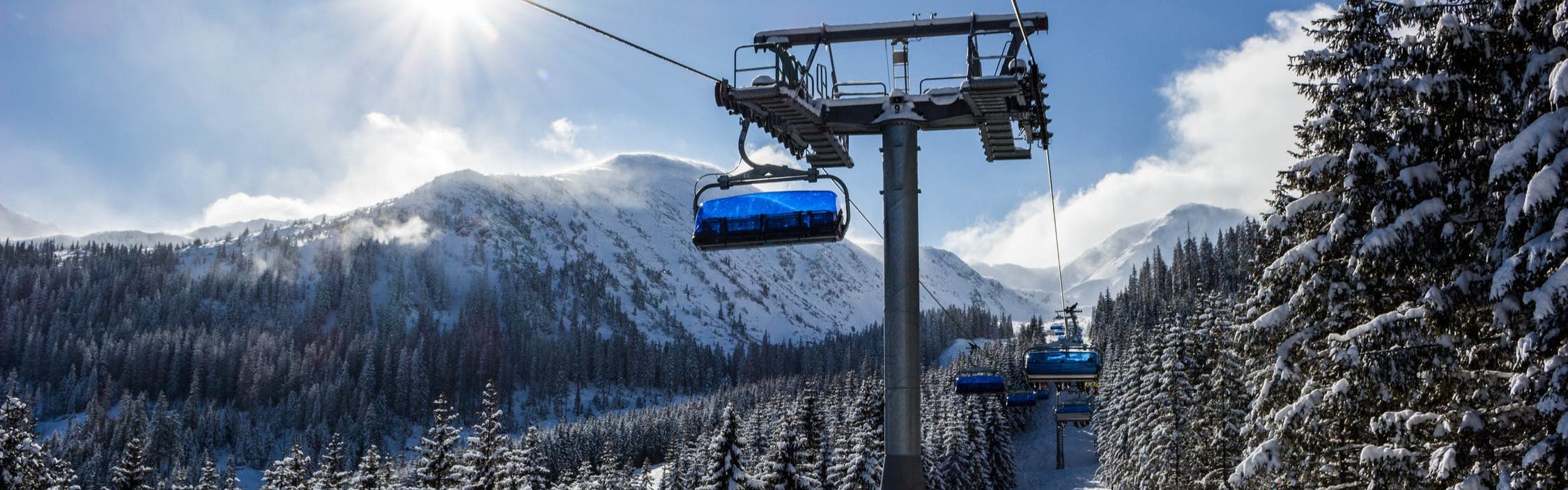 Chairlifts run up a tree-covered slope.