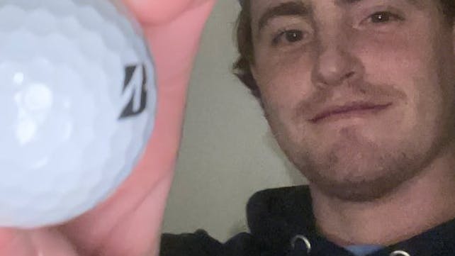 A man holding a Bridgestone Tour 2022 B XS Tiger Wood Edition Golf Ball.