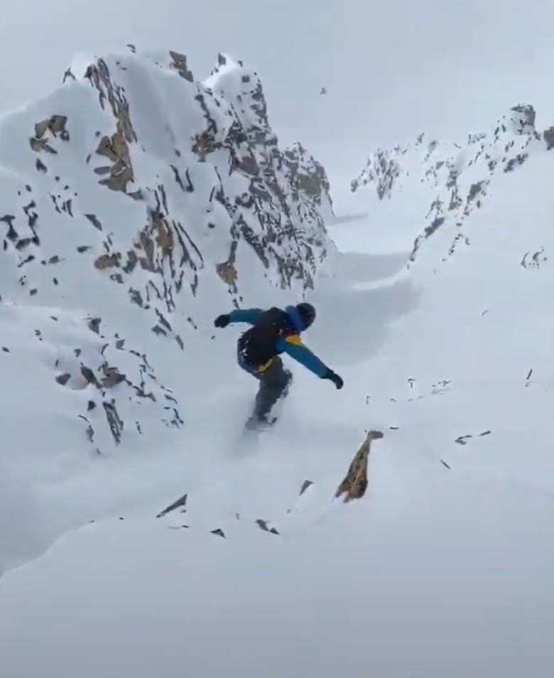 A snowboarder snowboarding down a narrow chute. 