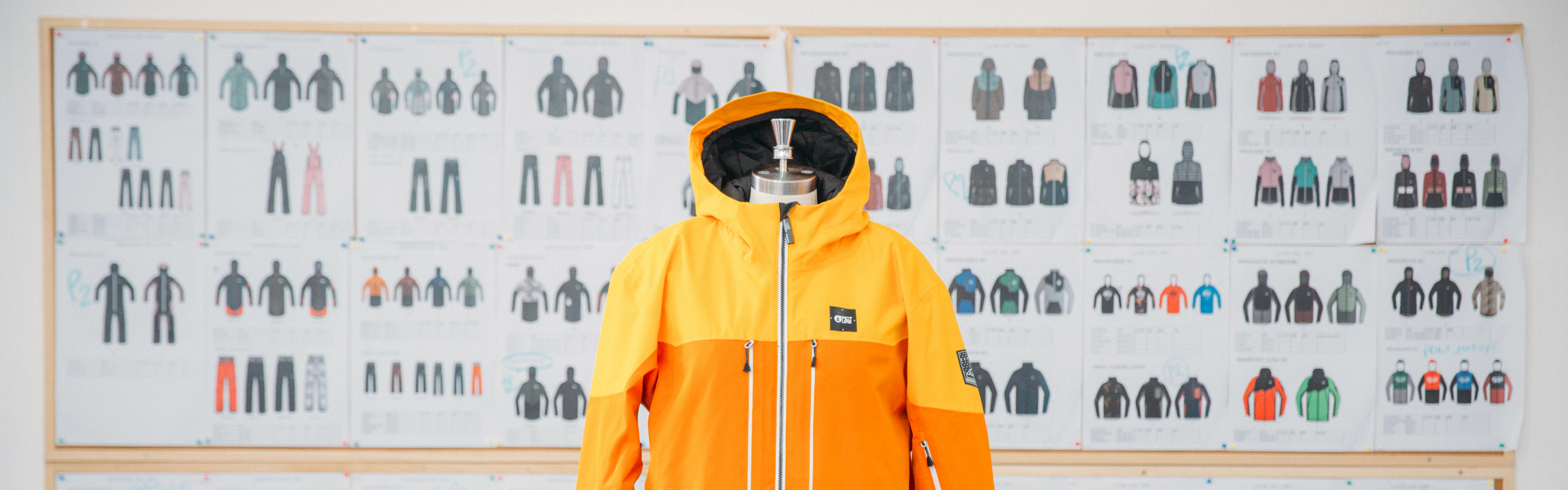 A bright orange jacket with a product design poster on the wall in the background